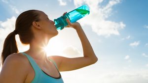 lady drinking water from a reusable sport bottle